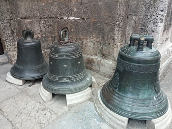 Three antique bronze church bells on stone pedestals
