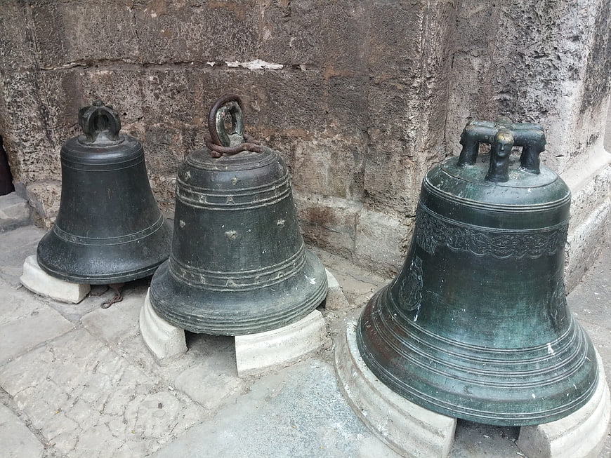 Three antique bronze church bells on stone pedestals