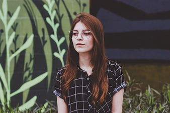Young Woman with Glasses Against Green Mural