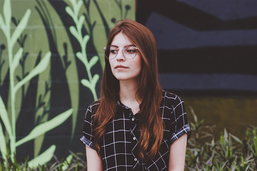 Young Woman with Glasses Against Green Mural