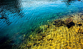 Crystal clear turquoise water with sunlit rocky bottom