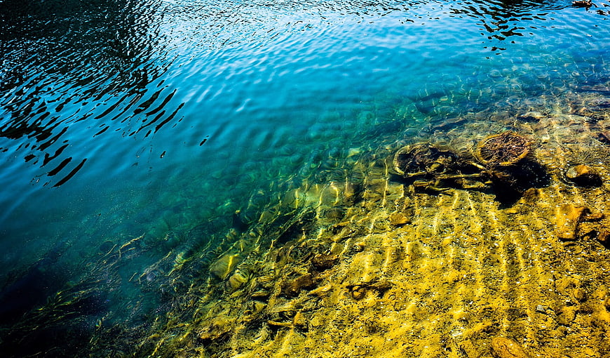 Crystal clear turquoise water with sunlit rocky bottom