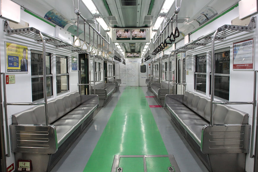 Empty subway car interior with green floor and gray seats
