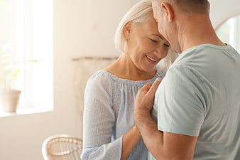 Happy senior couple embracing in bright home interior