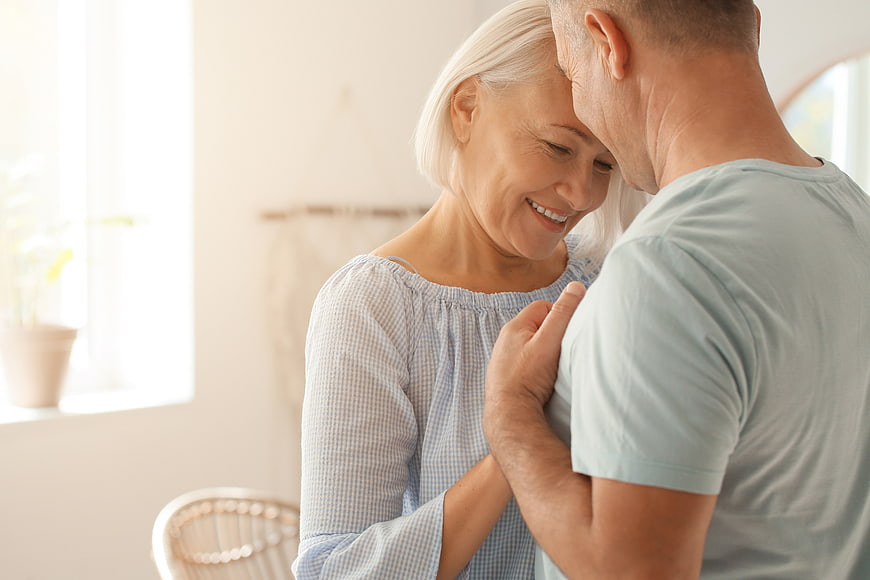 Happy senior couple embracing in bright home interior