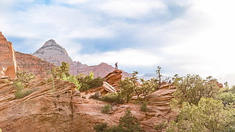 Hiker standing on red rock formation in desert landscape