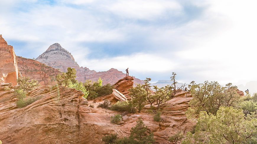 Hiker standing on red rock formation in desert landscape