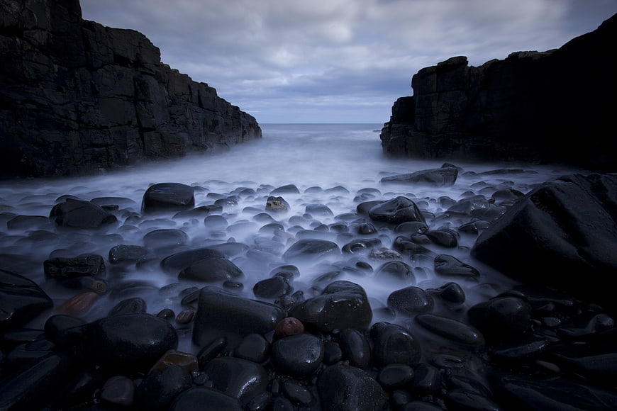 Long Exposure Dark Rocky Coastline with Misty Ocean Waves
