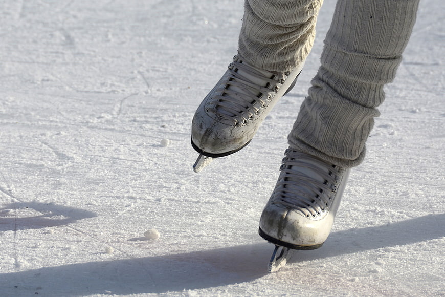 Close-up of worn white ice skates on outdoor rink