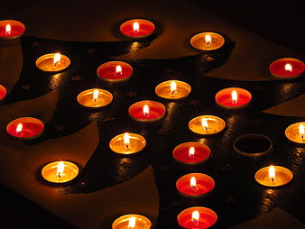 Advent tea lights arranged in a Christmas tree shape on a dark surface