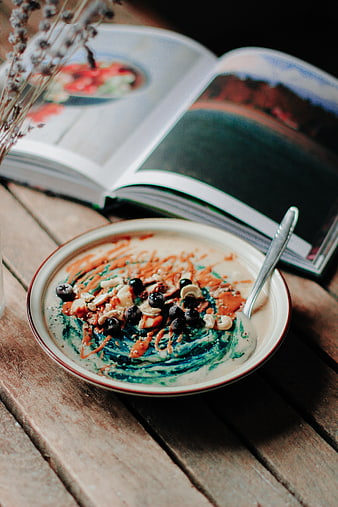 Spirulina oatmeal bowl with blueberries and nuts on wooden table