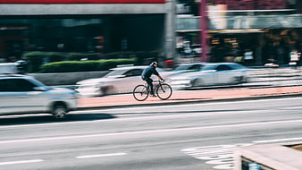 Cyclist riding fast on city street with motion blur