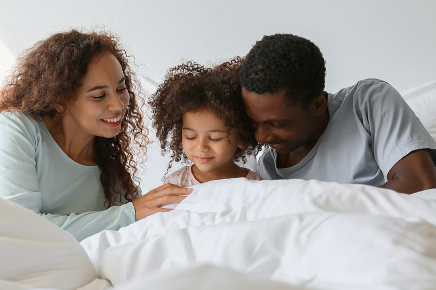Happy African American Family in Bed with Daughter