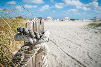 Rope on wooden post at sandy beach with dunes