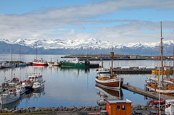 Husavik Harbor Boats With Snowy Mountains In Iceland