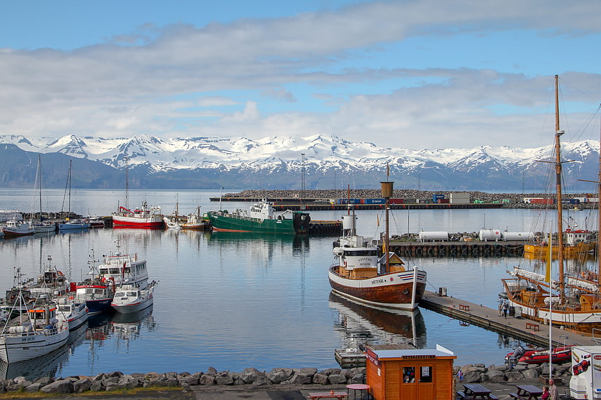 Husavik Harbor Boats With Snowy Mountains In Iceland
