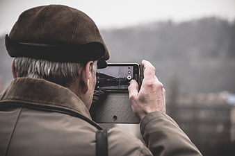 Senior man taking photo with smartphone outdoors