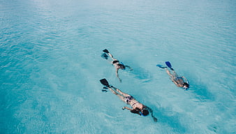 Aerial view of three people snorkeling in turquoise ocean water