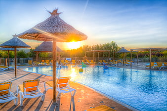Sunset at Resort Swimming Pool with Thatched Umbrellas