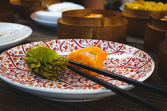 Colorful dim sum dumplings on patterned plate with chopsticks