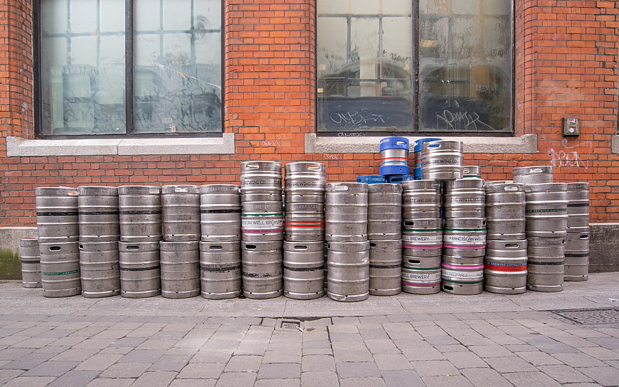 Stacked metal beer kegs on cobblestone street