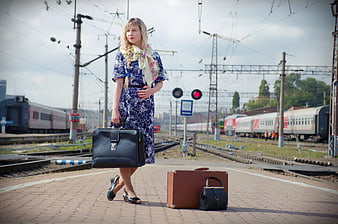 Woman with vintage suitcase and briefcase walking on railway platform