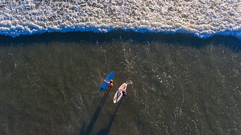 Aerial view of two surfers in ocean waves