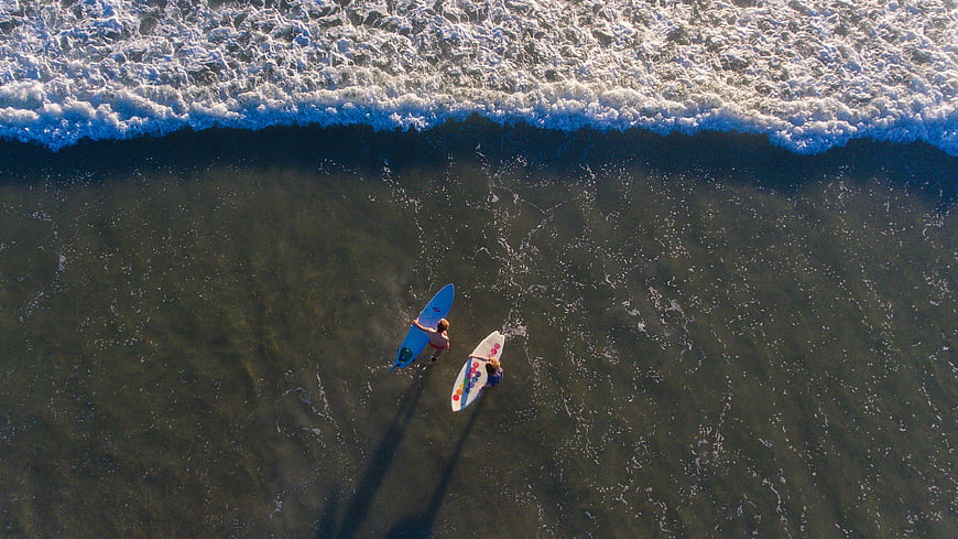Aerial view of two surfers in ocean waves
