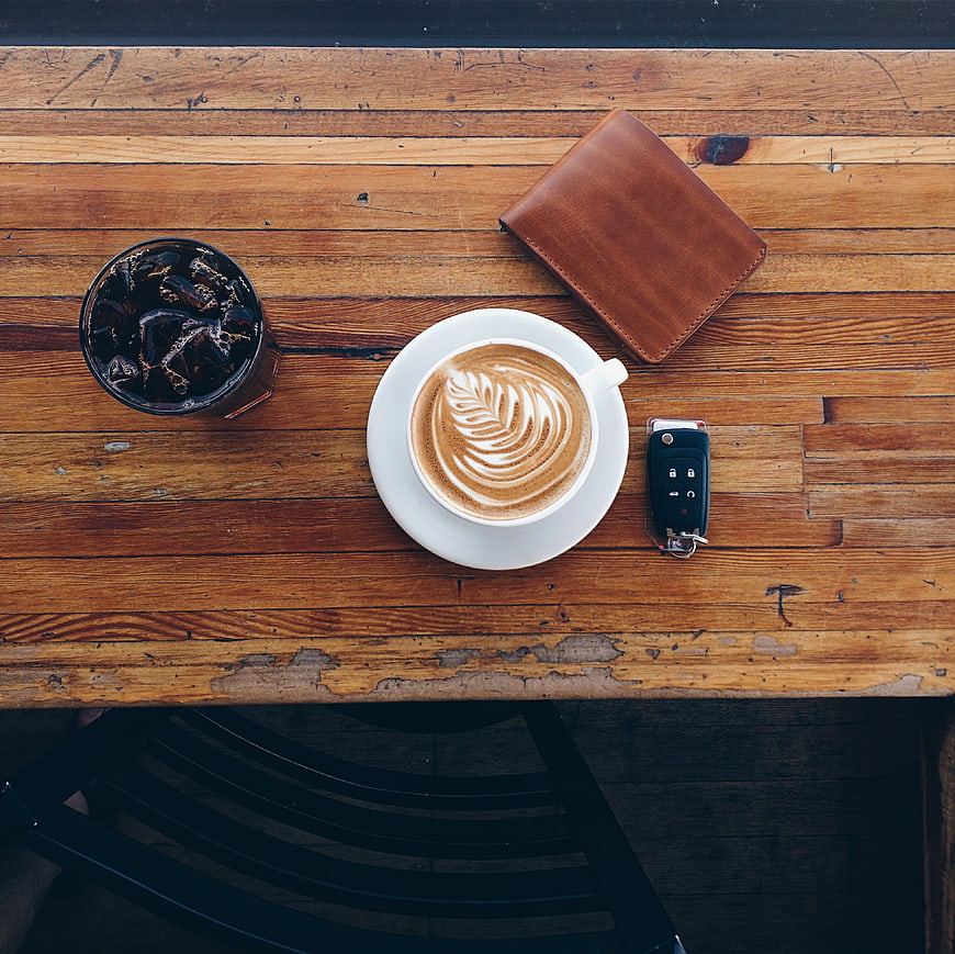 Top view of coffee, wallet, and car keys on wooden table