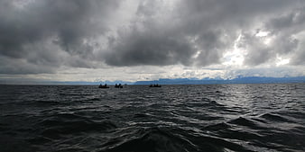 Dramatic stormy lake with small boats under dark clouds