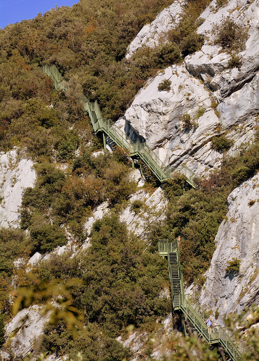 Green metal staircase winding up steep rocky mountain cliff