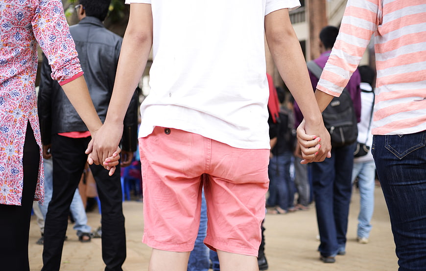 Group of friends holding hands in a circle outdoors