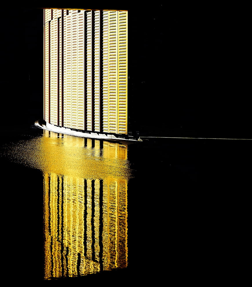 Golden skyscraper reflection in water at night