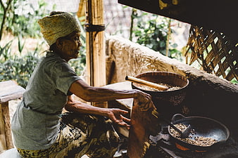 Senior woman roasting coffee beans in traditional rural kitchen