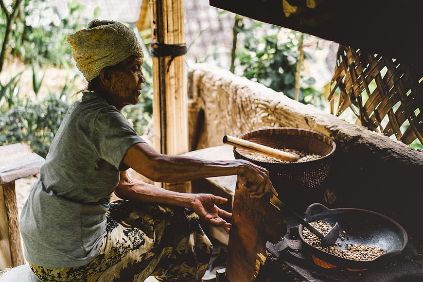 Senior woman roasting coffee beans in traditional rural kitchen