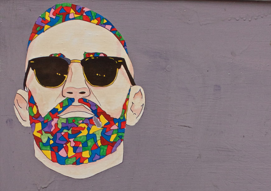 Colorful graffiti mural of a bearded man with sunglasses