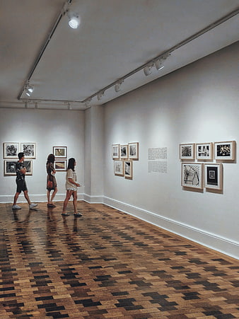 Visitors viewing art exhibition in gallery with parquet floor