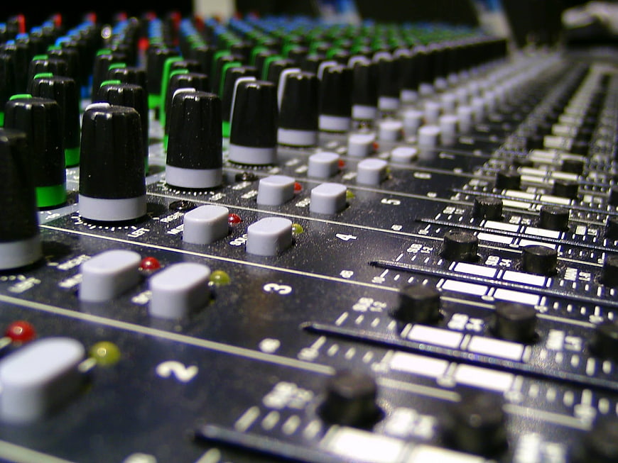 Close-up of professional audio mixing console with knobs and sliders