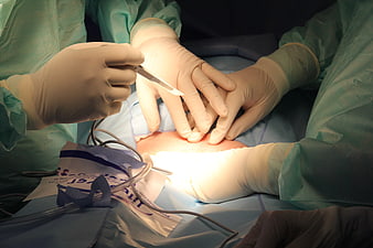 Close-up of surgical procedure with gloved hands and scalpel
