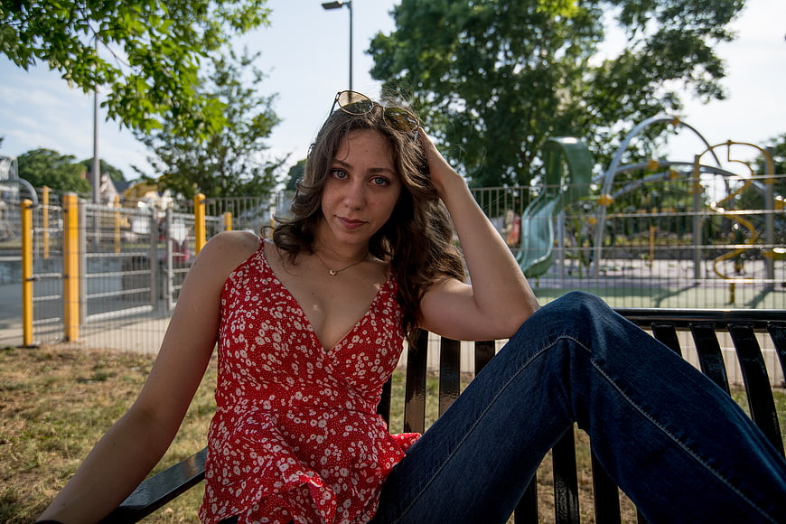 Young woman in red floral top sitting on park bench