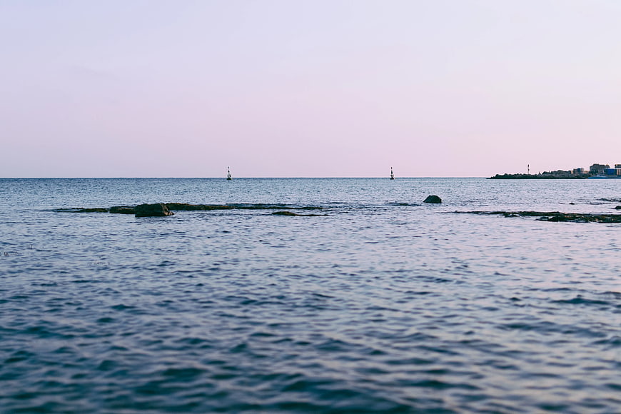 Calm Sea Horizon with Distant City and Navigation Buoys