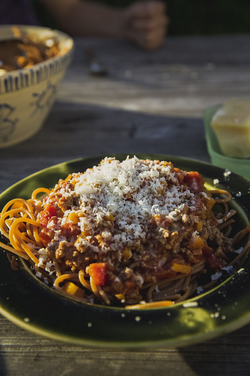 Close-up of spaghetti bolognese with parmesan cheese on a green plate