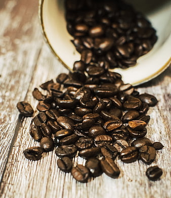 Spilled roasted coffee beans on rustic wooden table