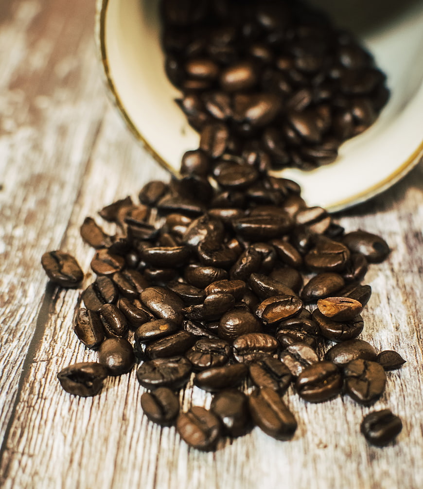 Spilled roasted coffee beans on rustic wooden table
