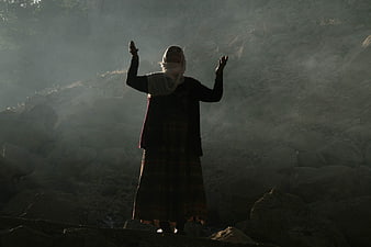Woman in Traditional Attire Praying in Misty Mountain Landscape