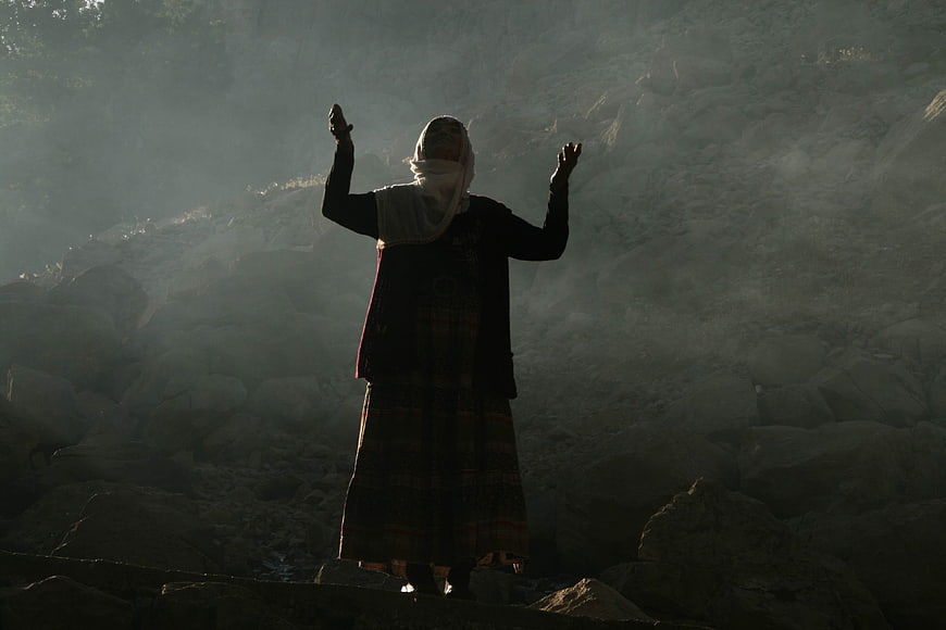 Woman in Traditional Attire Praying in Misty Mountain Landscape