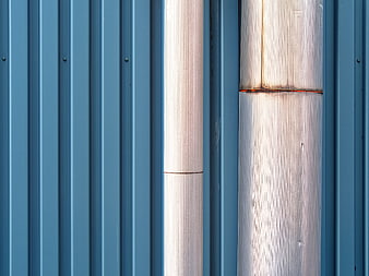 Abstract Blue Corrugated Metal Wall with Vertical Pipes