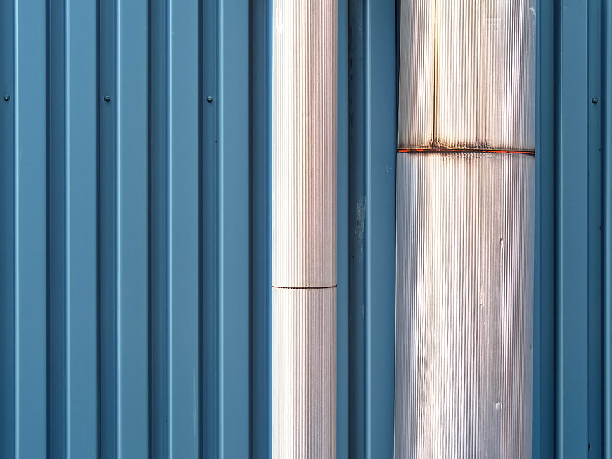 Abstract Blue Corrugated Metal Wall with Vertical Pipes