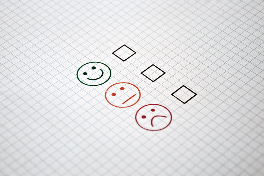 Customer satisfaction survey form with smiley faces and checkboxes on grid paper