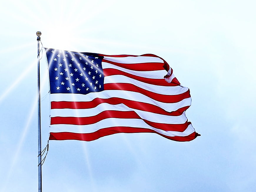 American Flag Waving Against Blue Sky with Sunburst